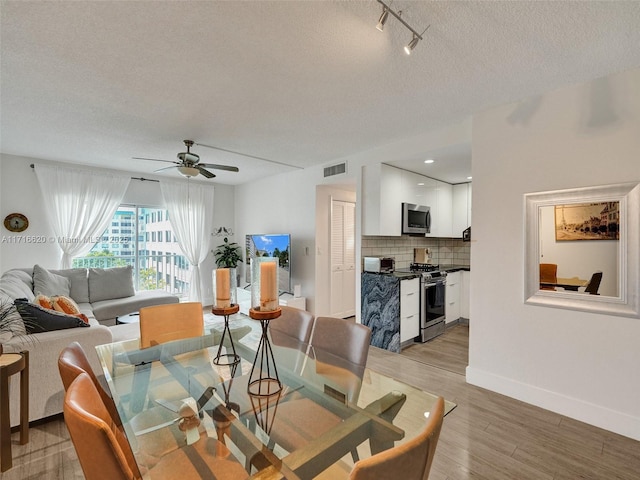 dining room with hardwood / wood-style floors, ceiling fan, and a textured ceiling