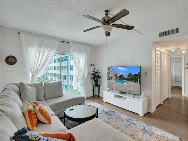 living room featuring ceiling fan, wood-type flooring, and a textured ceiling