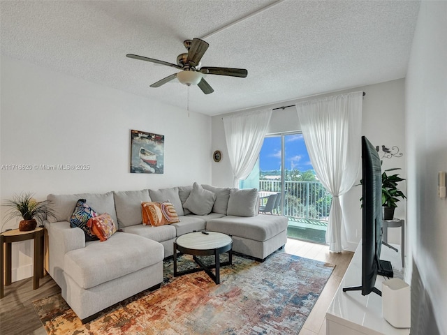 living room featuring wood-type flooring, a textured ceiling, and ceiling fan