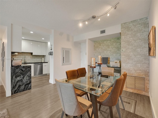 dining space with light hardwood / wood-style flooring, a textured ceiling, and sink