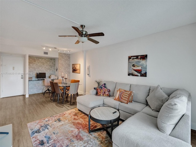 living room with ceiling fan, hardwood / wood-style floors, and a textured ceiling