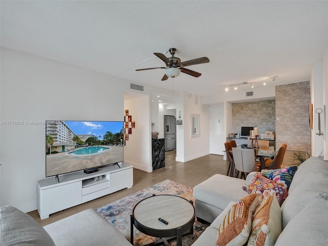 living room featuring ceiling fan, a textured ceiling, and hardwood / wood-style flooring