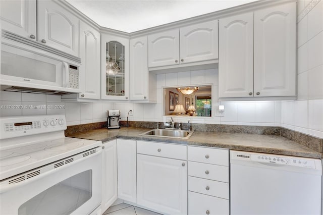 kitchen featuring white appliances, backsplash, white cabinets, sink, and light tile patterned floors