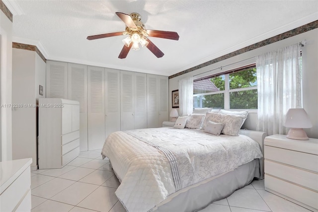 bedroom with light tile patterned floors, a closet, ceiling fan, and crown molding