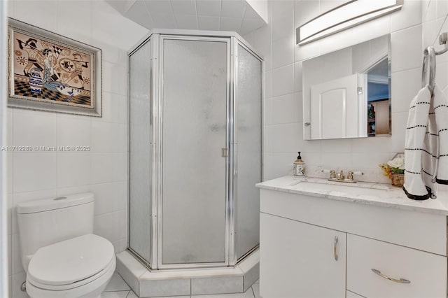 bathroom with vanity, an enclosed shower, tile walls, and toilet