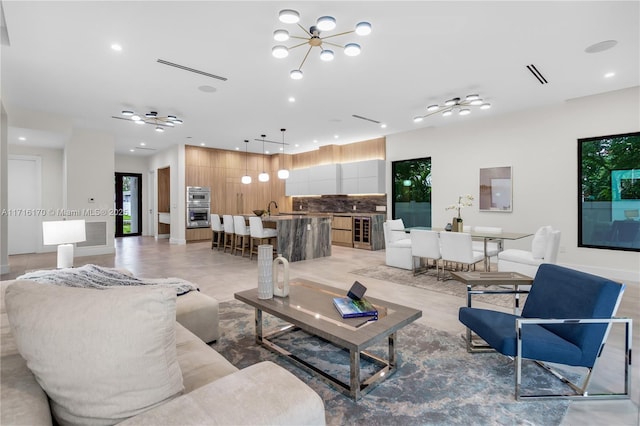 living room featuring ceiling fan with notable chandelier, sink, and wine cooler