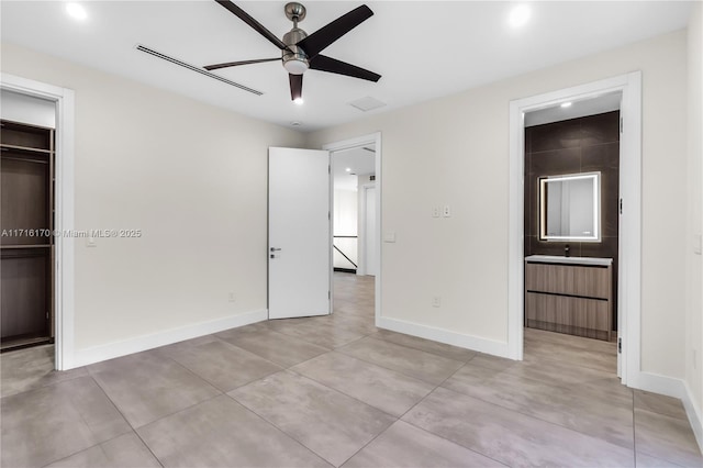 unfurnished bedroom with ensuite bath, ceiling fan, a closet, and a spacious closet