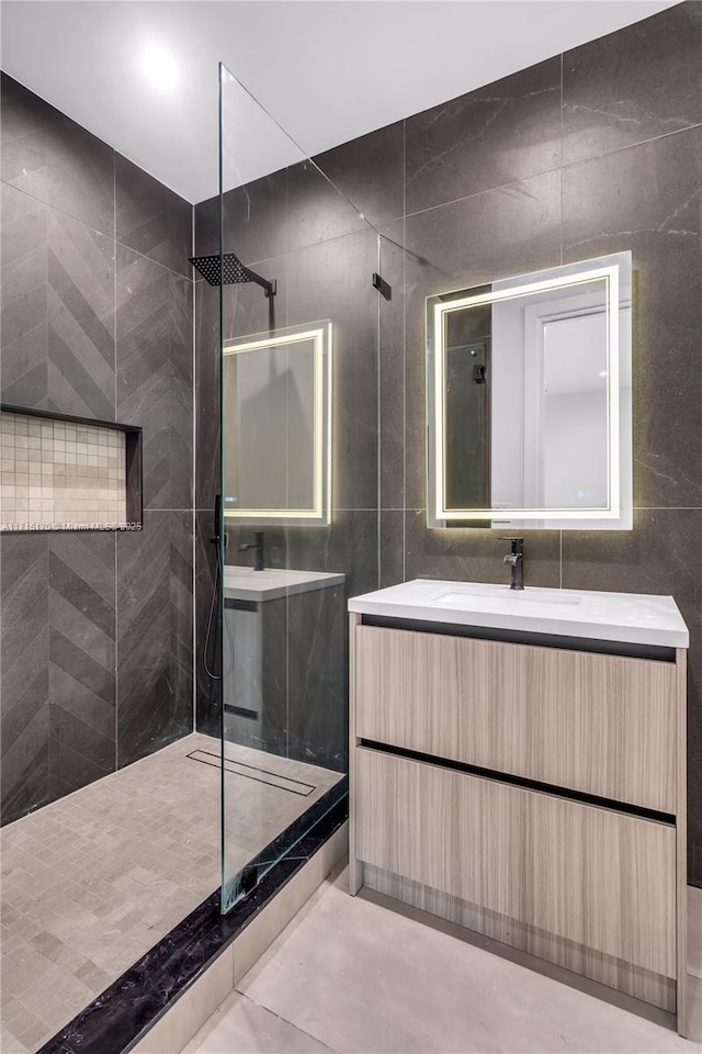 bathroom featuring tiled shower, vanity, and tile walls