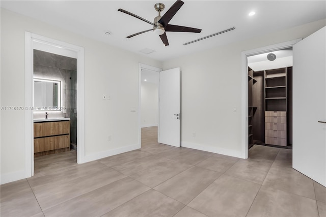 unfurnished bedroom featuring sink, ceiling fan, a spacious closet, connected bathroom, and a closet