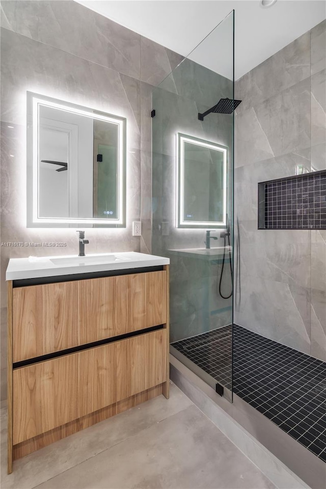 bathroom with a tile shower and vanity