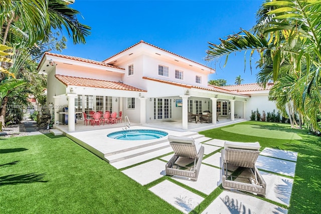 back of house with french doors, a swimming pool with hot tub, a yard, and a patio