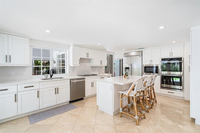 kitchen featuring sink, a breakfast bar, a center island, built in appliances, and white cabinets