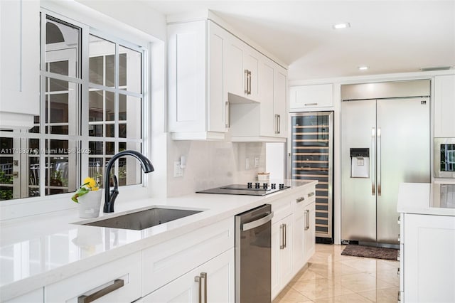 kitchen with sink, light stone counters, tasteful backsplash, appliances with stainless steel finishes, and white cabinets