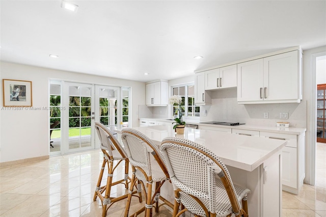 kitchen featuring tasteful backsplash, black electric stovetop, white cabinets, a kitchen island, and french doors