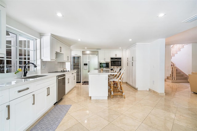 kitchen with sink, a kitchen bar, decorative backsplash, a center island, and stainless steel appliances