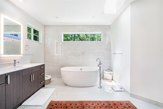 bathroom featuring vanity, tile patterned flooring, a tub, and tile walls