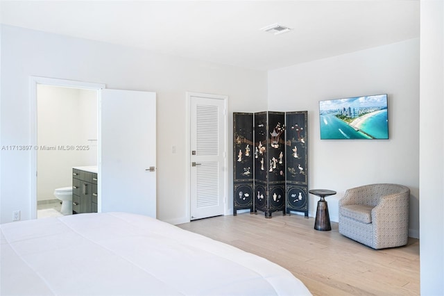 bedroom featuring light wood-type flooring and ensuite bath