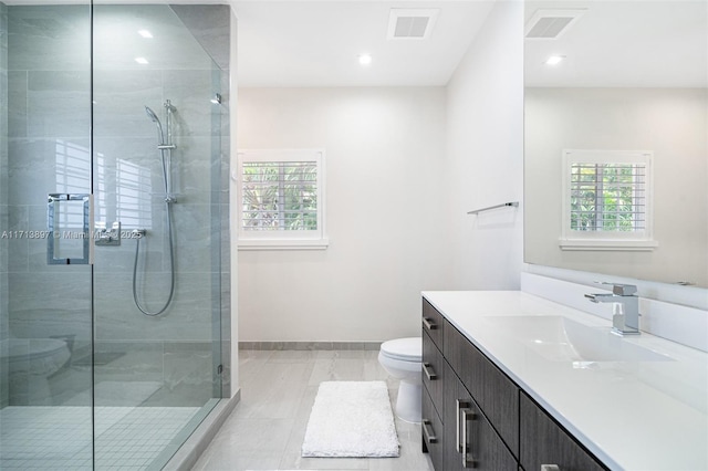 bathroom featuring a healthy amount of sunlight, toilet, a shower with door, and vanity