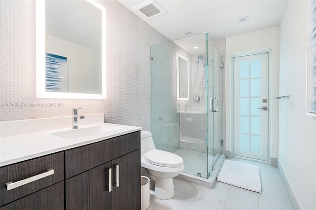 bathroom featuring a shower with door, vanity, tile patterned floors, and toilet