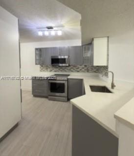 kitchen with sink, stainless steel appliances, backsplash, light hardwood / wood-style floors, and white cabinets