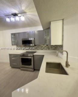 kitchen featuring hardwood / wood-style floors, stainless steel appliances, gray cabinets, and sink