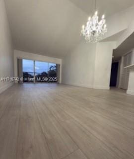 unfurnished living room with wood-type flooring and a notable chandelier