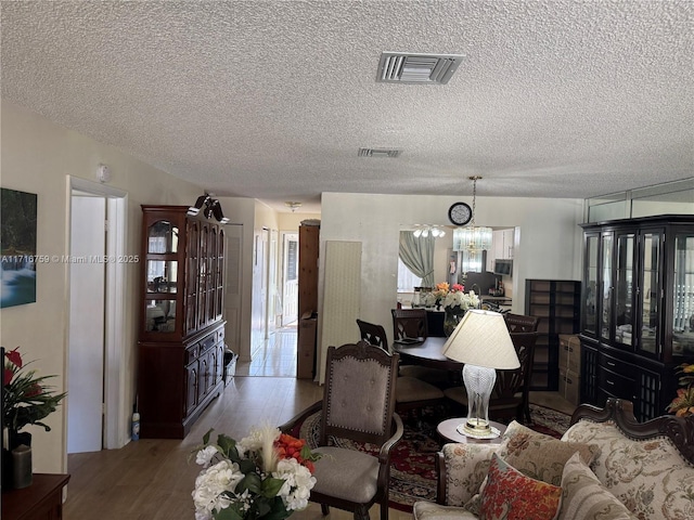 living room with hardwood / wood-style flooring, a textured ceiling, and a chandelier