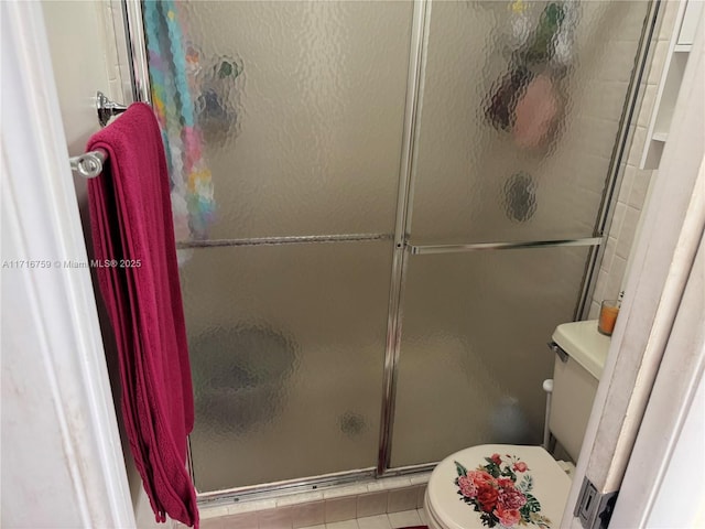 bathroom featuring tile patterned flooring, toilet, and a shower with shower door