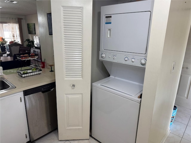 washroom with a textured ceiling, light tile patterned floors, and stacked washer / dryer