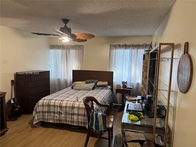 bedroom with hardwood / wood-style flooring, ceiling fan, a textured ceiling, and multiple windows