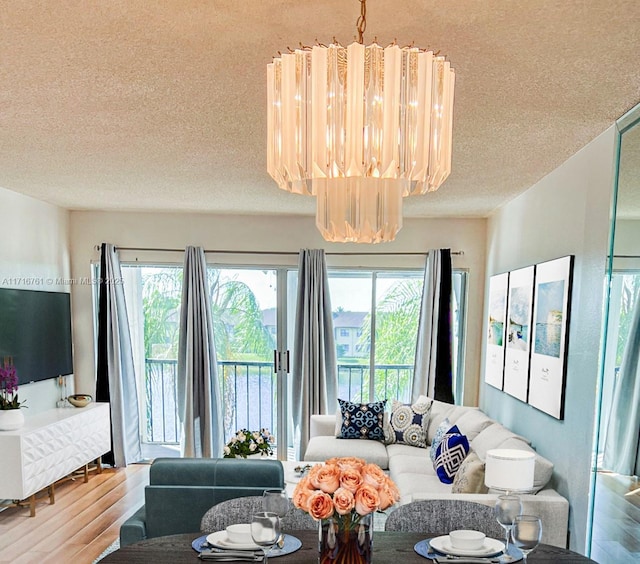 living room featuring wood-type flooring, a textured ceiling, and an inviting chandelier