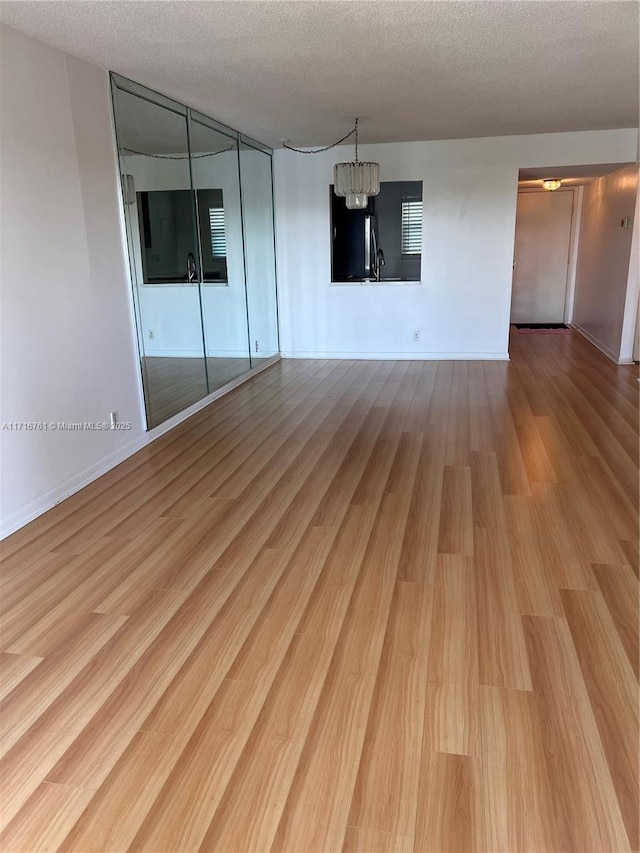 spare room with a chandelier, hardwood / wood-style floors, a textured ceiling, and sink