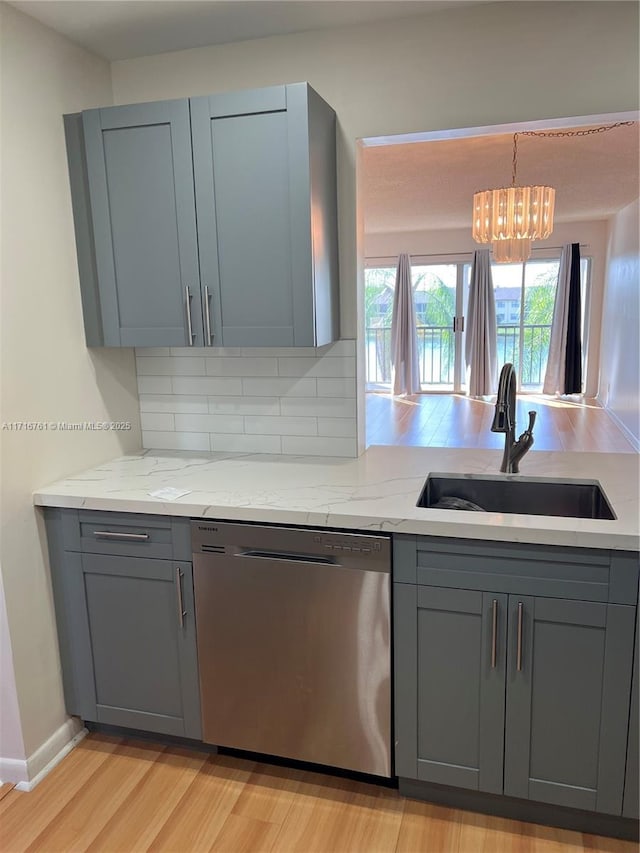 kitchen featuring gray cabinetry, light stone countertops, dishwasher, sink, and decorative light fixtures