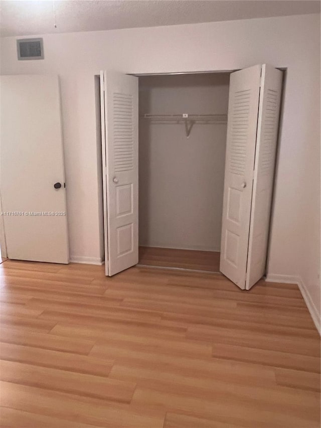 unfurnished bedroom featuring light hardwood / wood-style flooring and a closet