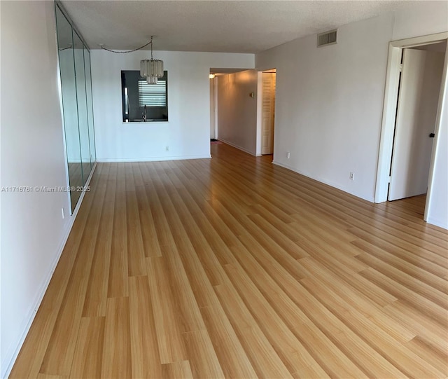 unfurnished room with a chandelier, sink, and light hardwood / wood-style floors