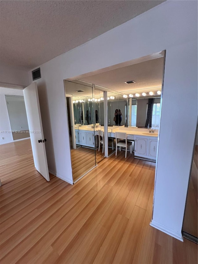 hallway featuring a textured ceiling, light hardwood / wood-style flooring, and sink