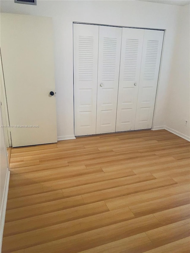 unfurnished bedroom featuring light hardwood / wood-style floors and a closet