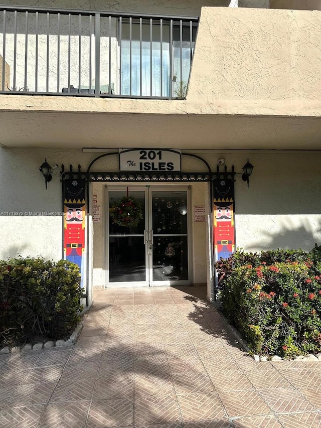 view of exterior entry with a balcony and french doors