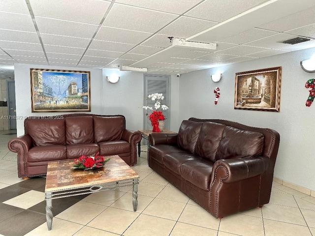 living room with a paneled ceiling and light tile patterned floors