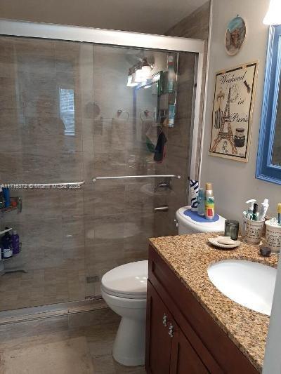 bathroom featuring an enclosed shower, vanity, and toilet