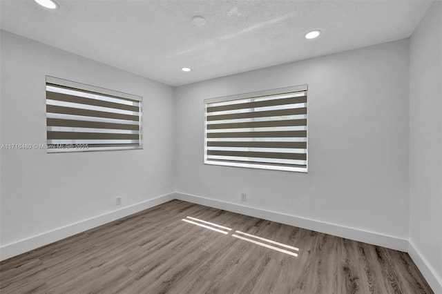 unfurnished room with hardwood / wood-style floors and a textured ceiling