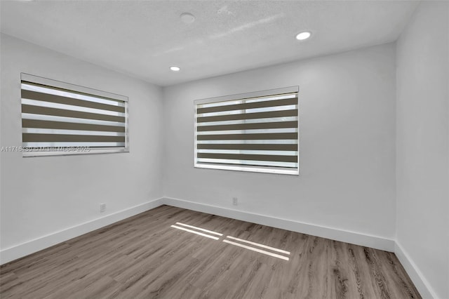 empty room with a textured ceiling and light hardwood / wood-style flooring