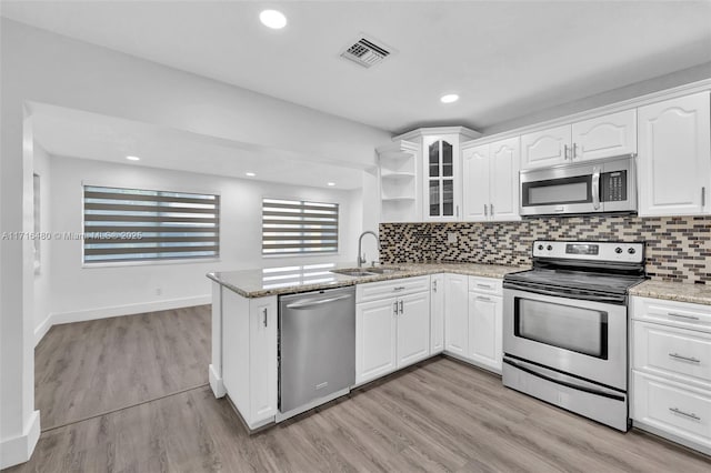 kitchen with kitchen peninsula, stainless steel appliances, light stone countertops, and sink