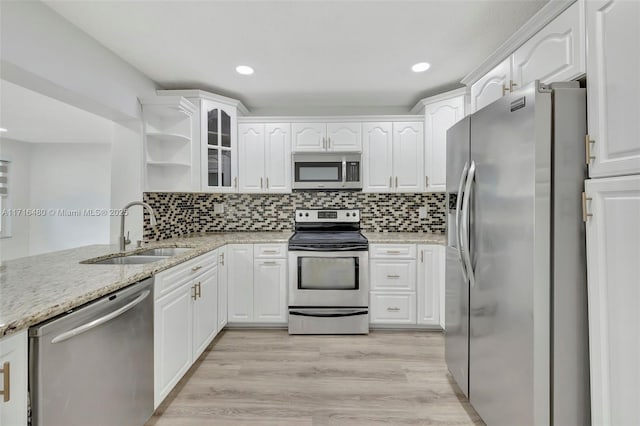 kitchen with sink, stainless steel appliances, light stone counters, white cabinets, and light wood-type flooring