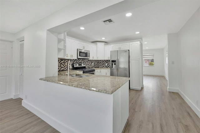 kitchen featuring light stone counters, kitchen peninsula, light hardwood / wood-style floors, white cabinets, and appliances with stainless steel finishes