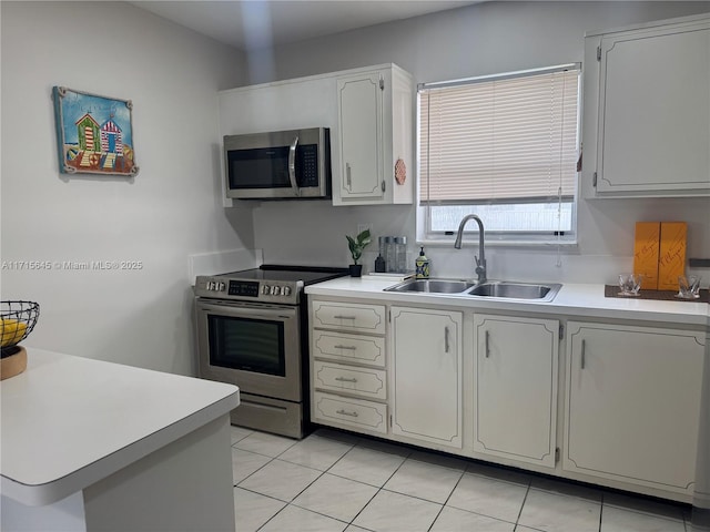 kitchen with white cabinetry, appliances with stainless steel finishes, light tile patterned flooring, and sink