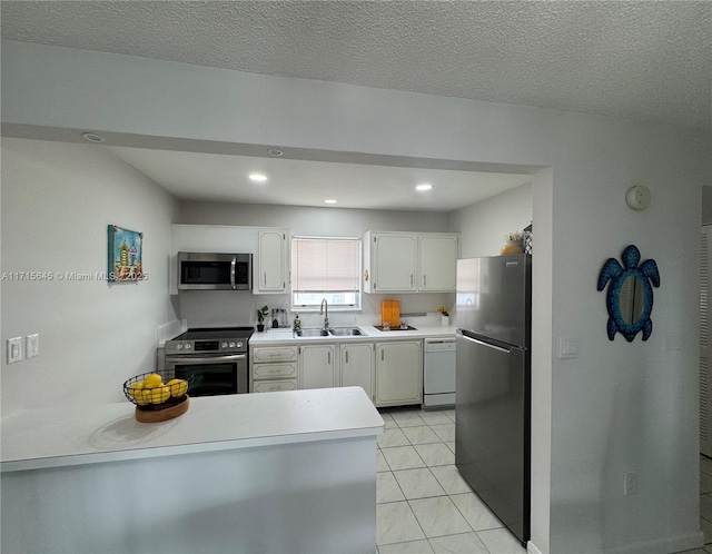 kitchen featuring appliances with stainless steel finishes, white cabinetry, sink, light tile patterned floors, and a textured ceiling