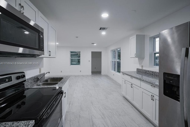 kitchen with sink, light stone countertops, white cabinetry, and stainless steel appliances