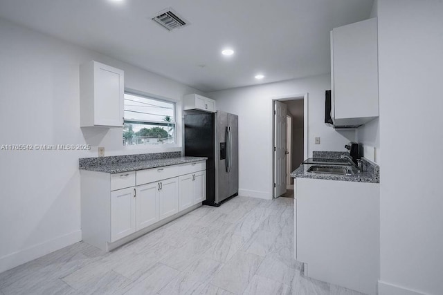 kitchen with dark stone countertops, white cabinetry, sink, and stainless steel refrigerator with ice dispenser