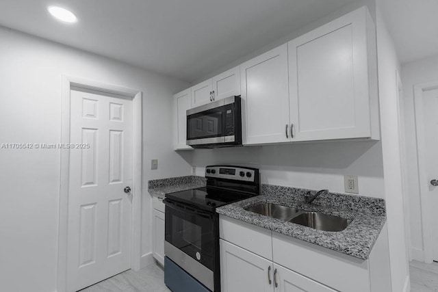 kitchen featuring light stone countertops, white cabinetry, sink, and appliances with stainless steel finishes